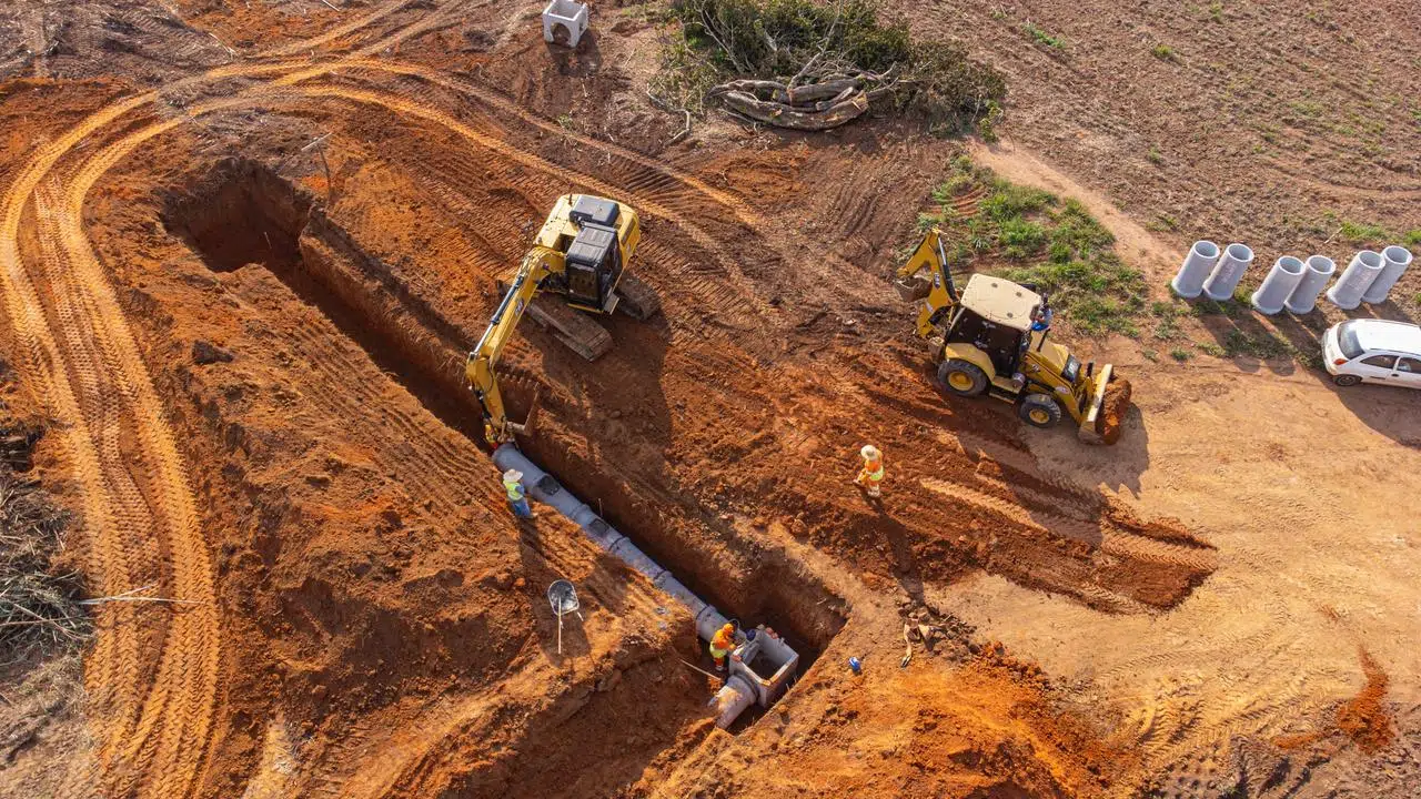 Escavadeira instalando tubo de drenagem